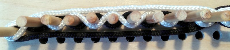 Wooden pegs with black and white threads woven between them