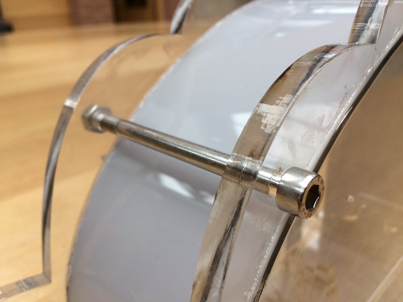 Close up of long steel nut and bolt holding clear pieces of acrylic together across a bridge of coloured acrylic