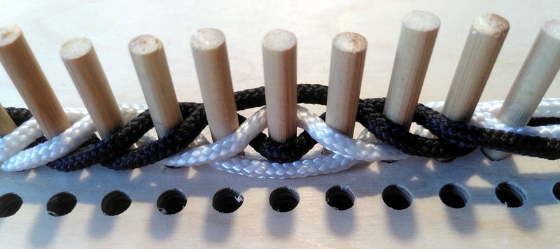 9 visible pegs, with black and white threads woven betweent them