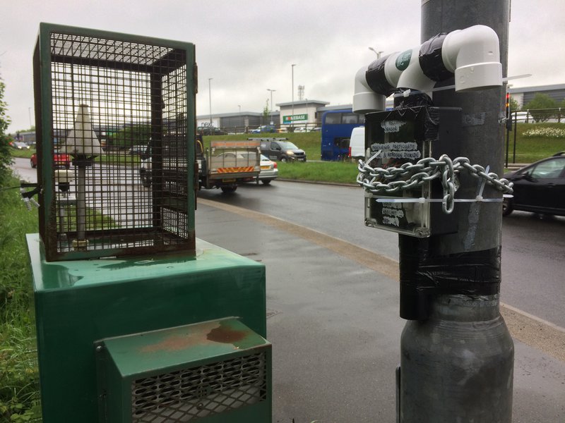 Photo of cornwall council reference station next to a busy road, with our sensor chained to a lamp post next to it