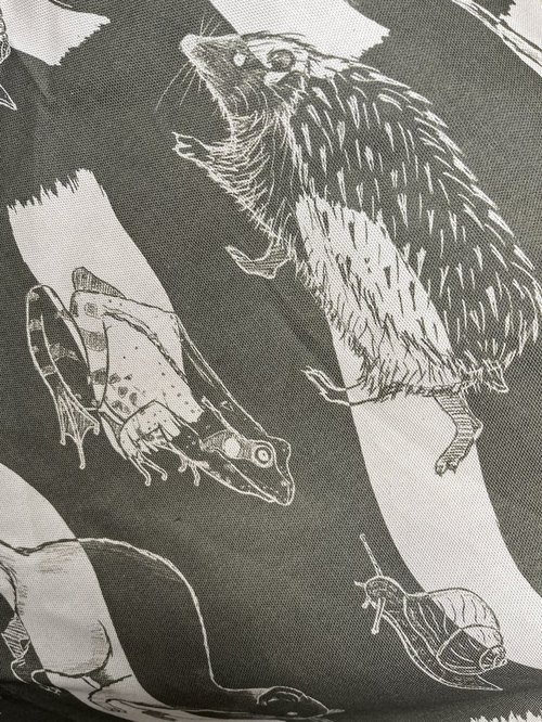fabric printed with illustrated hedgehog, frog, snail, and a weasel just visible
